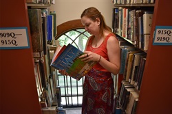female reading in library aisle