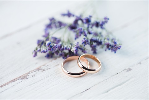 two gold rings next to flowers
