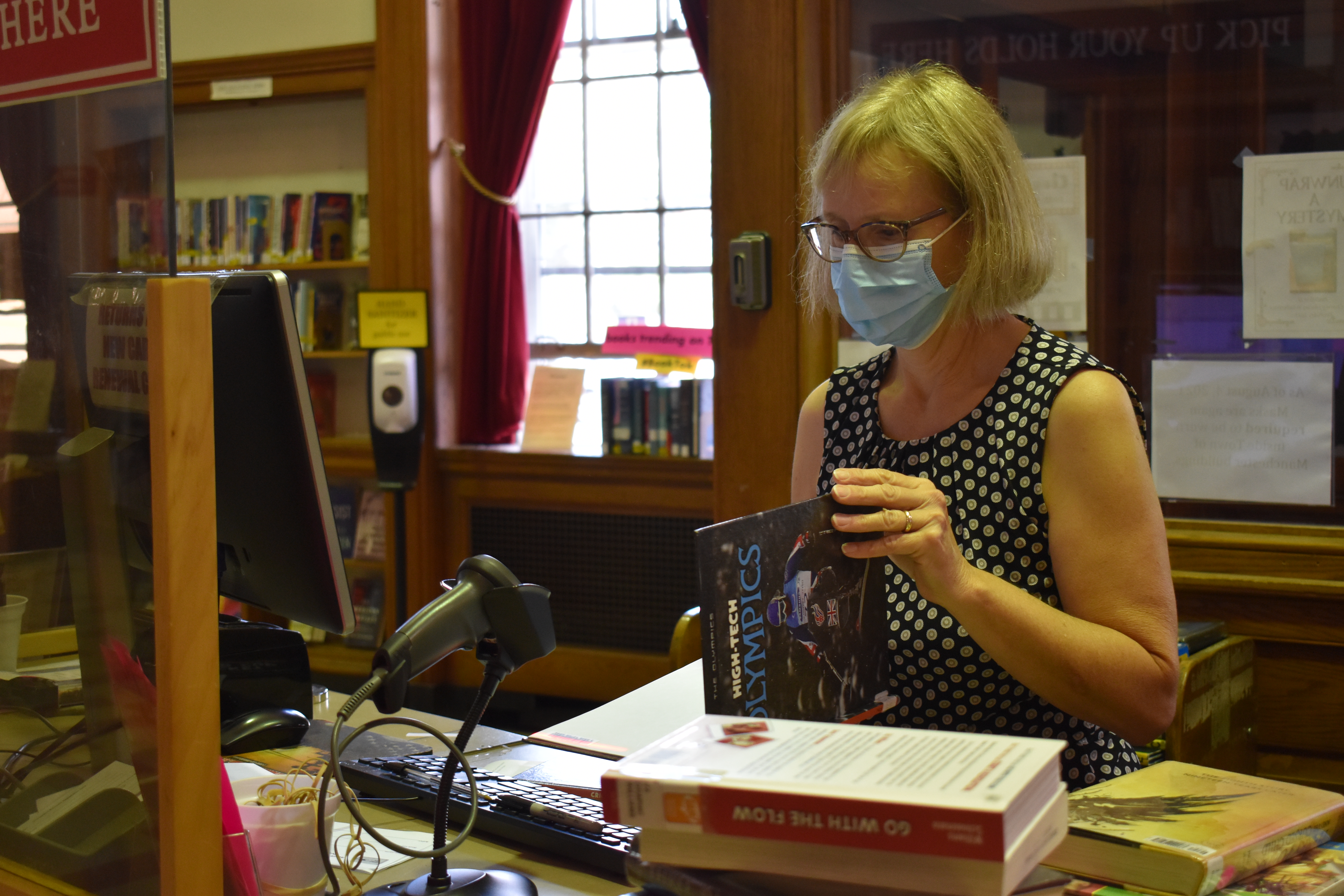 female librarian checking books at desk